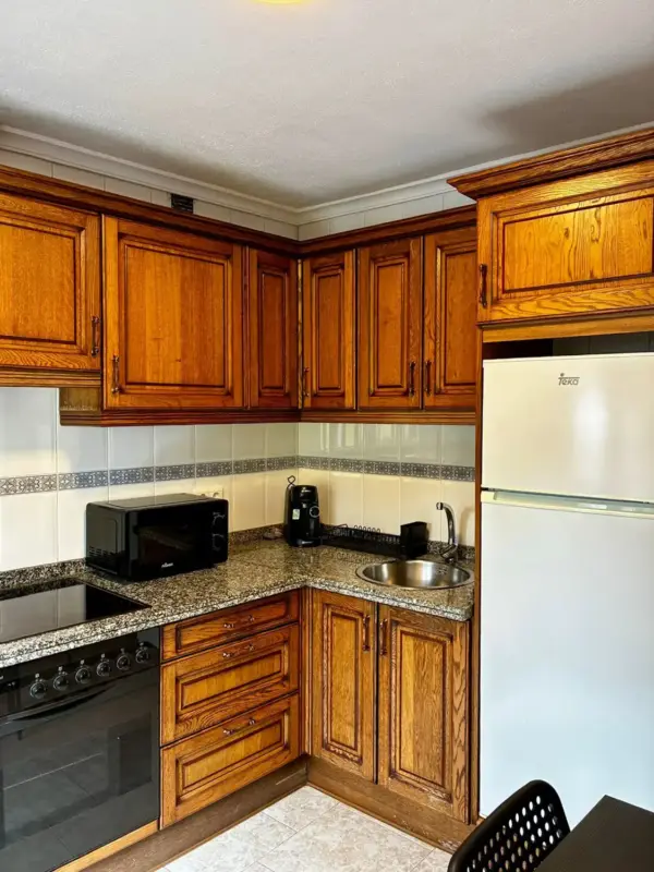 Cocina equipada con nevera y muebles de madera en Apartamentos Villa García