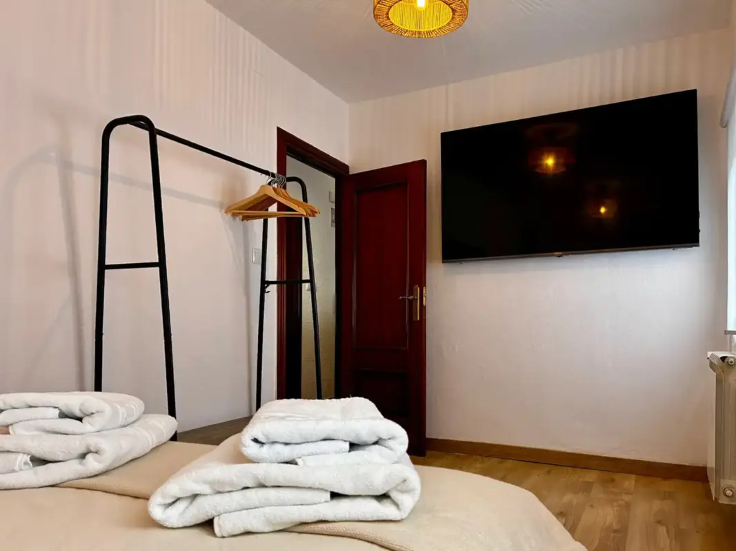 Dormitorio principal con televisión y toallas en Apartamentos Villa García